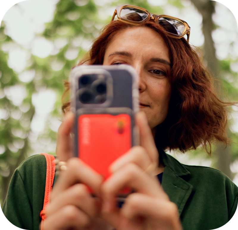 A person is holding a smartphone with a Monzo card visible in the case, looking at the screen.