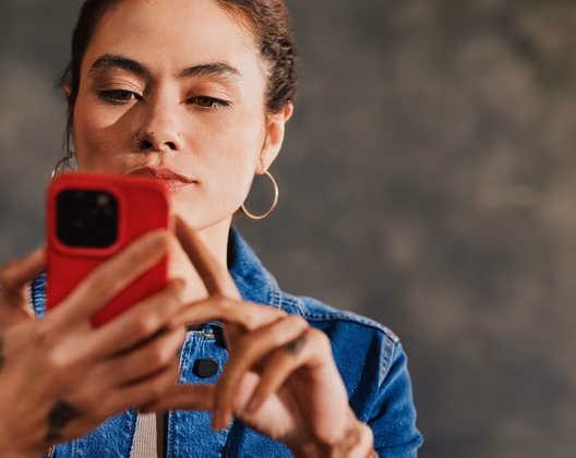 Person using a phone with a Hot Coral case