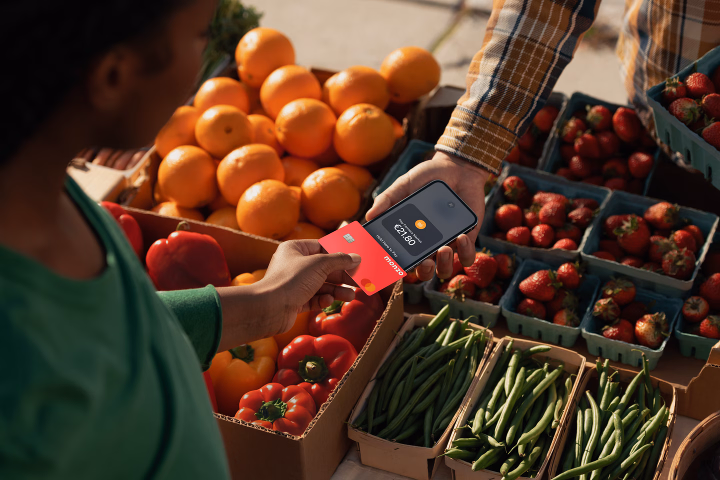 Customer paying €21.80 at a fruit and vegetable market stall by tapping a Monzo card on the vendor's phone.