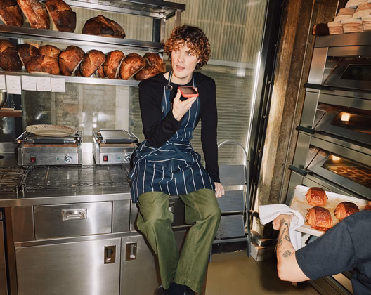 Man speaking into a mobile on a speakerphone in a bakery