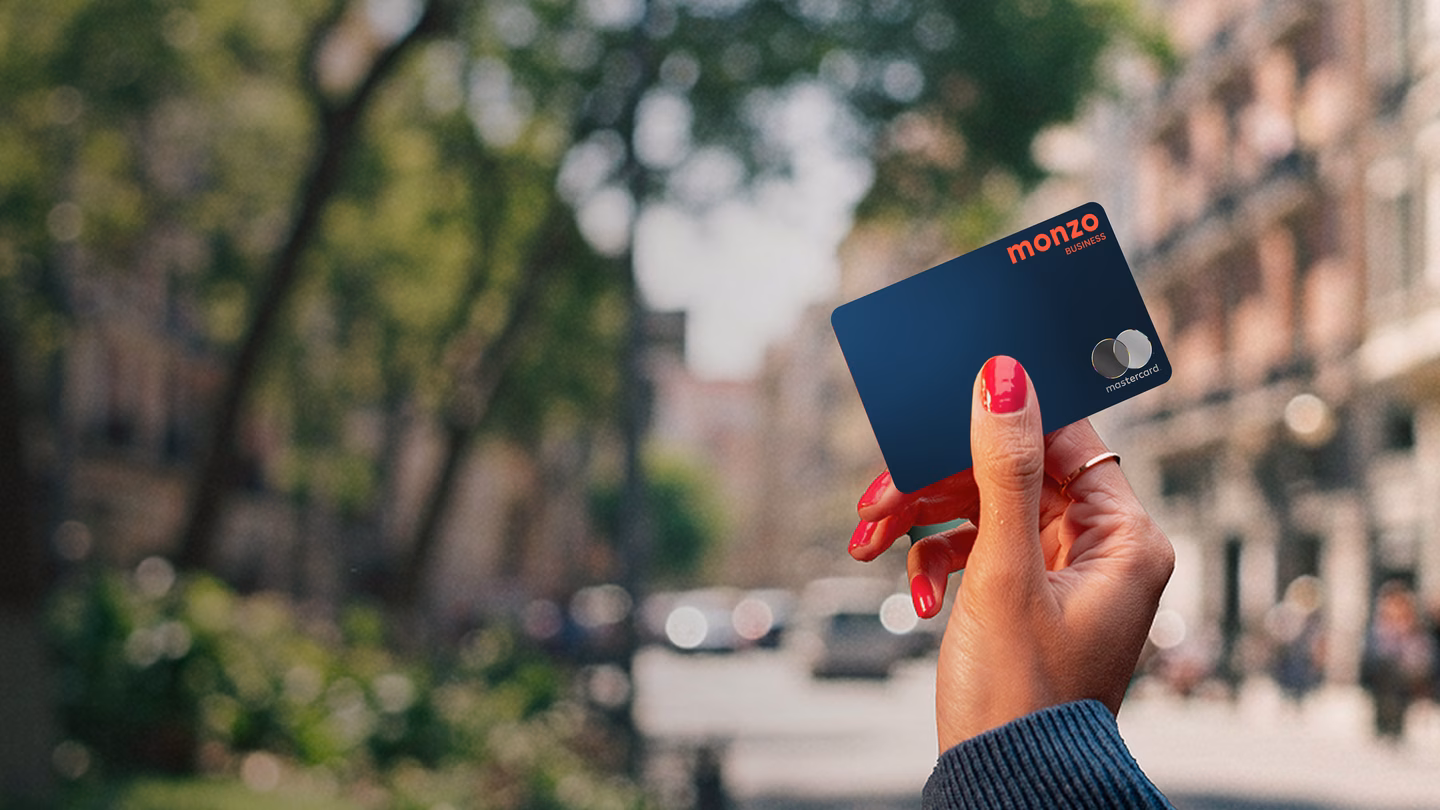 Hand with nail polish holding a Monzo Business debit card