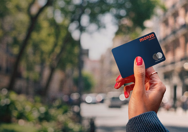 Hand with nail polish holding a Monzo Business debit card