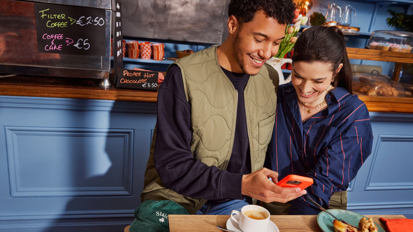 Couple in a cafe checking their phone over coffee