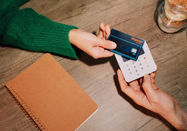 A customer taps their Monzo Business Expense card on a compact card reader to make a contactless payment.