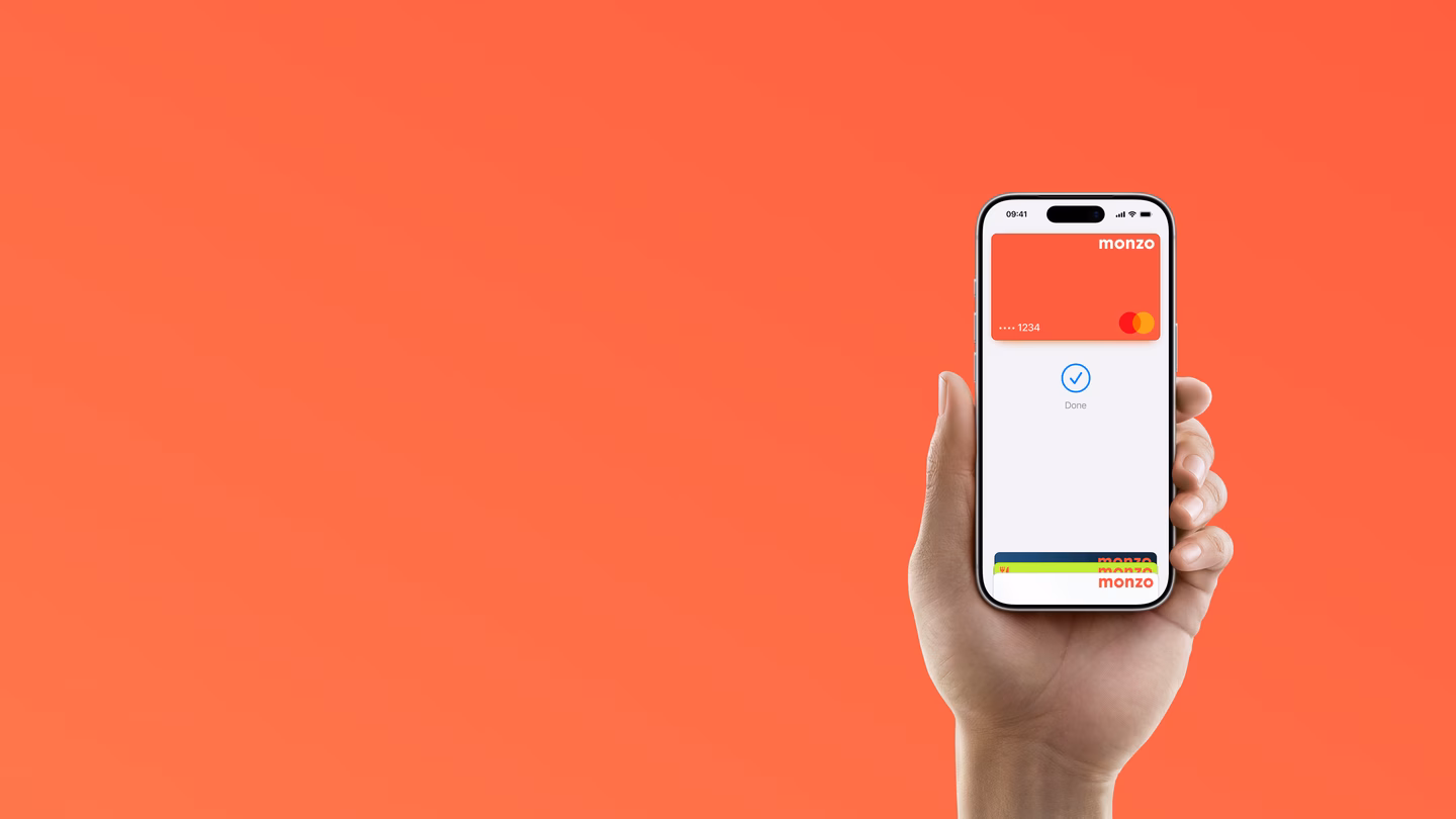 A hand holding an iPhone showing a completed Apple Pay payment with a Monzo card