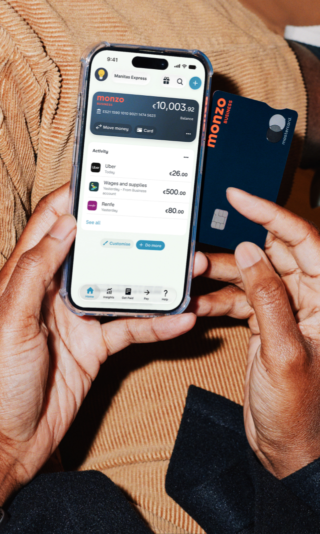 Manos sosteniendo un teléfono que muestra una pantalla de una cuenta de Monzo Business.
