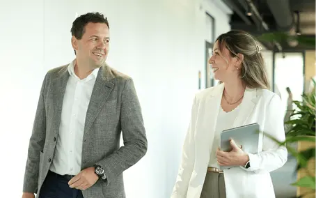 Two colleagues discussing a project during a walk through the office and coordinating the next project management steps.