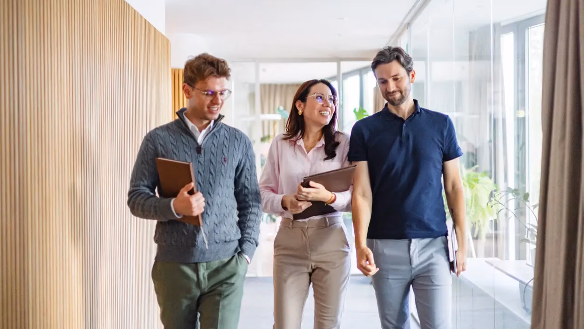 Drei Studierende laufen durch ein modernes Büro zu einem Termin