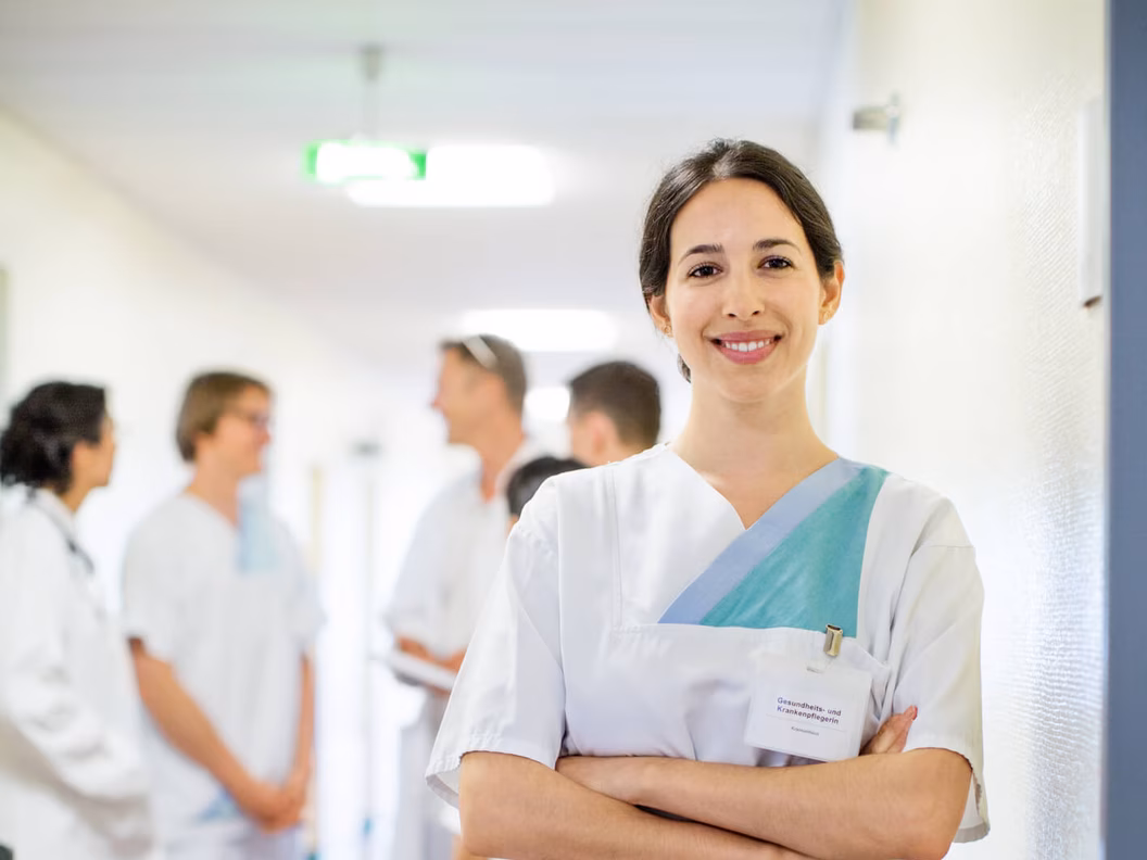 Portrait Krankenschwester mit Kollegen und Kolleginnen im Hintergrund