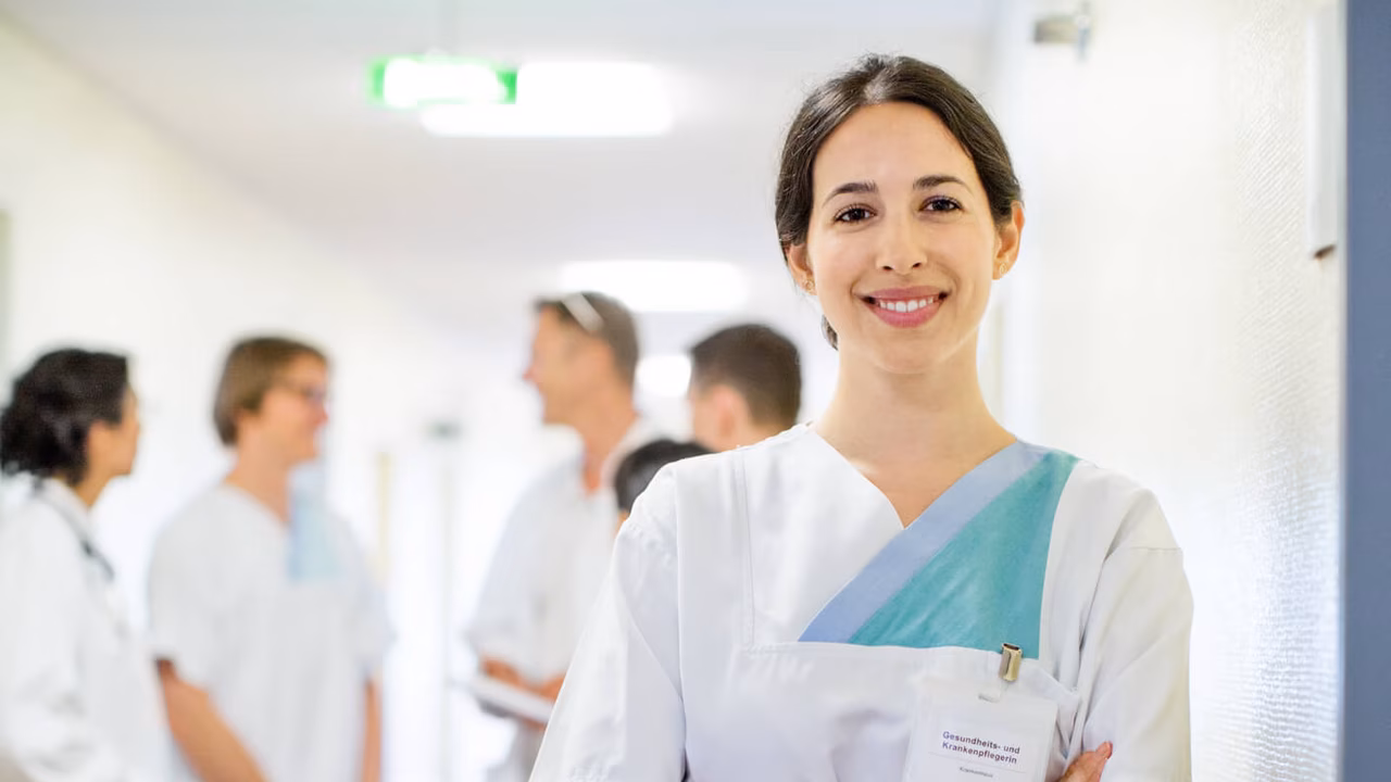 Portrait Krankenschwester mit Kollegen und Kolleginnen im Hintergrund