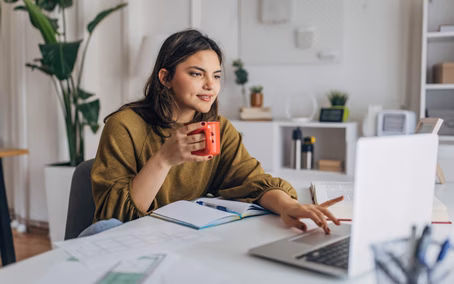Junge Frau genießt Kaffee während der Arbeit von zu Hause aus