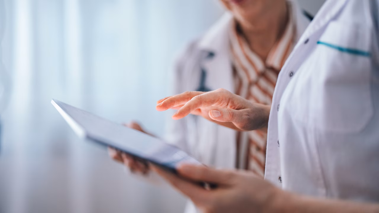 Medizinisches Fachpersonal arbeiten zusammen mit Informationen am iPad