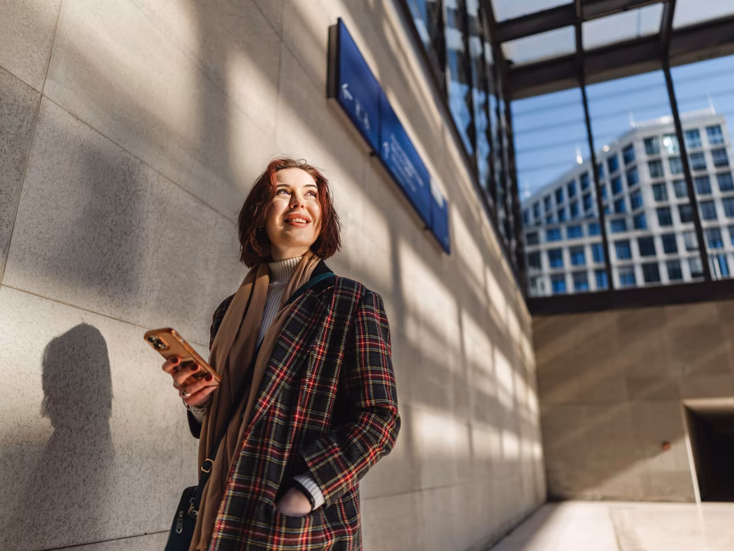 Glückliche Frau mit Smartphone in der zeitgenössischen Berliner Architektur