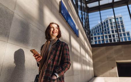Happy woman with a smartphone amid contemporary Berlin architecture