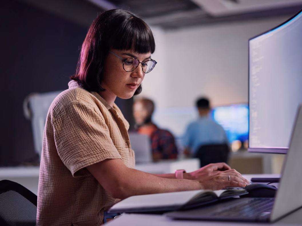 IT development Mitarbeiterin am Arbeitsplatz mit Laptop und curved Bildschirm