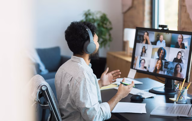 Mann mit Kopfhörern, der an einem virtuellen Gruppentreffen teilnimmt