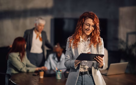 Frau mit Tablet vor einem Team im Kontext sicherer LLM-Hosting-Lösungen