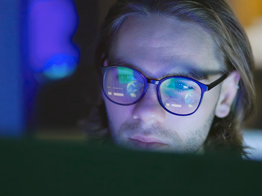 Close-up of an IT employee whose screen is reflected in their glasses