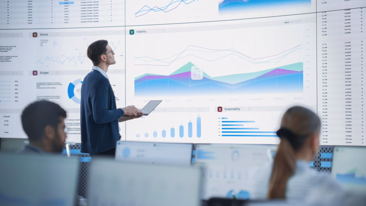 Männlicher Senior Data Analyst, der Finanzinformationen und Berichte auf einem großen digitalen Bildschirm überprüft