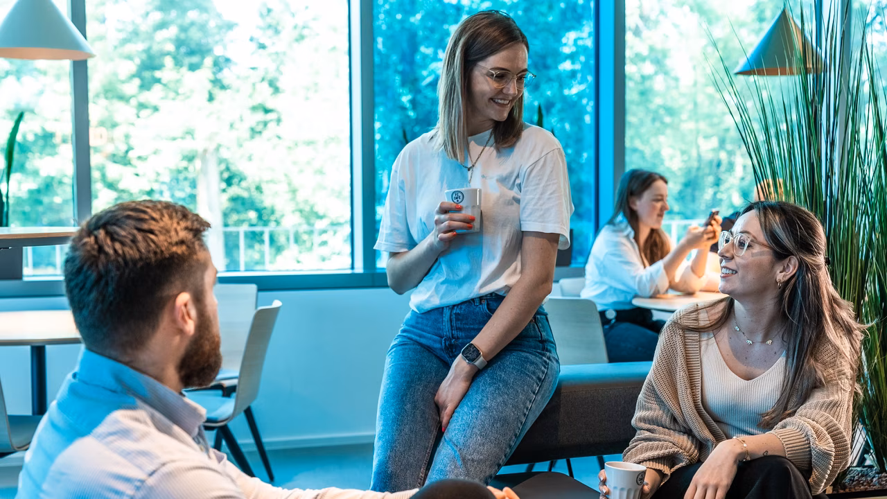 Diverses Team im Aufenthaltsraum eines Campus gemeinschaftlich am Reden