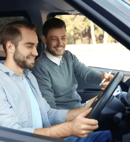 A happy driving instructor holding a clipboard beside a learner driver, representing the daily tuition business protected by legal expenses insurance.