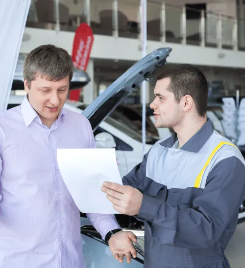 A customer reviewing a repair estimate or service invoice with a professional mechanic at a car garage.