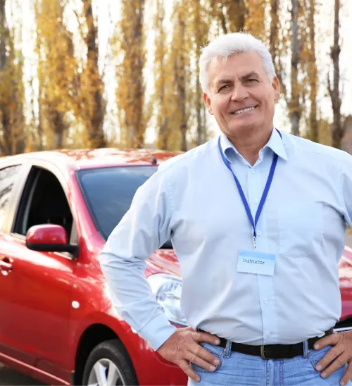 Smiling driving instructor standing beside a tuition car, representing specialist driving instructor insurance and support for UK instructors.