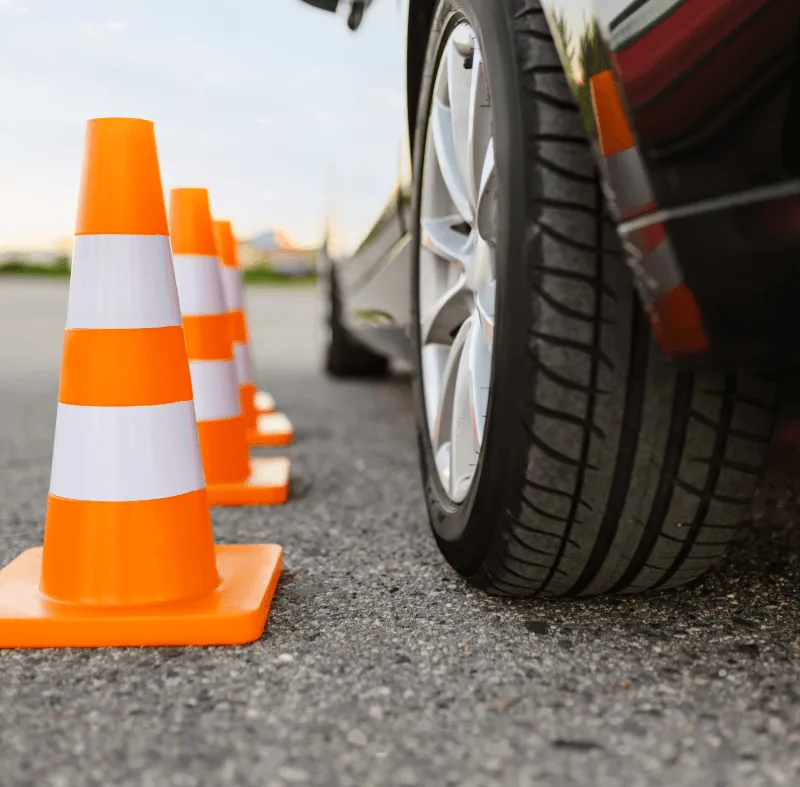 Orange traffic cones next to a car wheel during driver training, representing driving school insurance and learner driver risk.