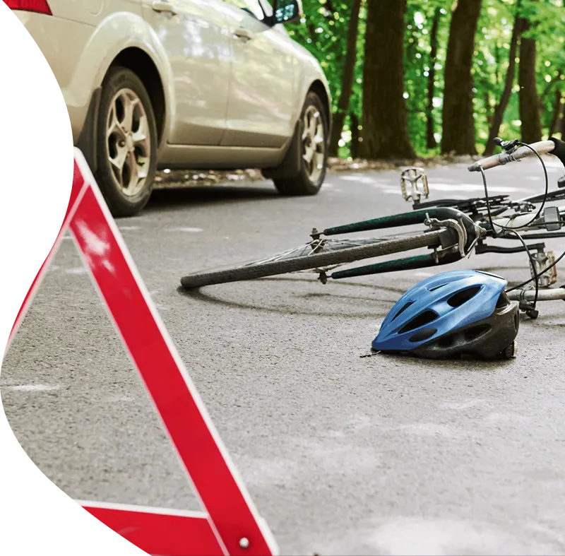 A red warning triangle placed on the road next to a fallen bicycle and helmet, illustrating a third-party accident requiring public liability cover.