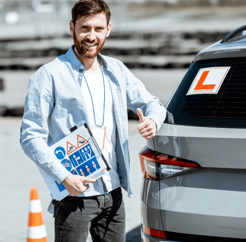 Driving instructor standing beside a learner driver car with L plates, representing specialist driving instructor insurance from BG Insurance.