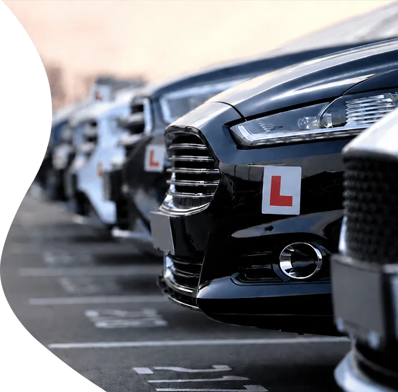 A fleet of modern replacement tuition cars with learner plates parked in a row, representing guaranteed dual-control courtesy vehicles for driving instructors.