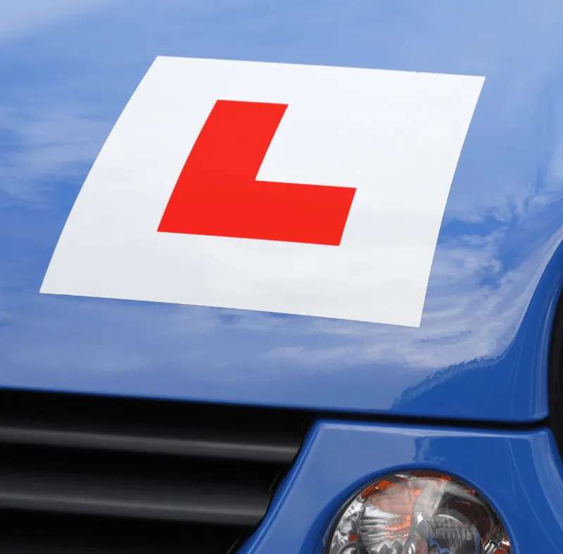 Close-up of a blue car with a red L learner driver plate displayed on the bonnet.