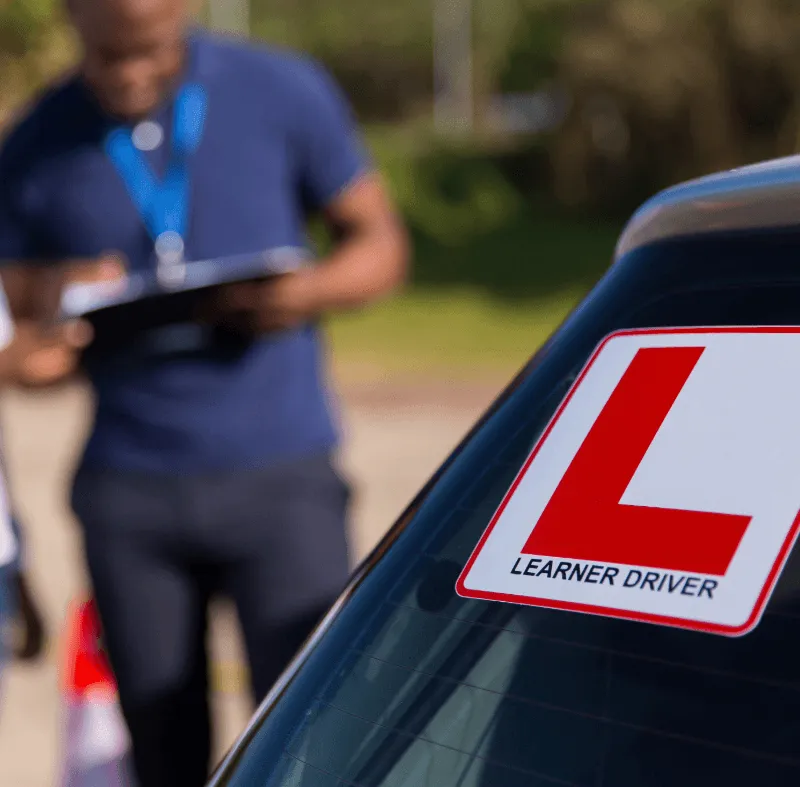 Learner driver L plate on the rear window of a driving school car, representing fleet insurance for driving schools.