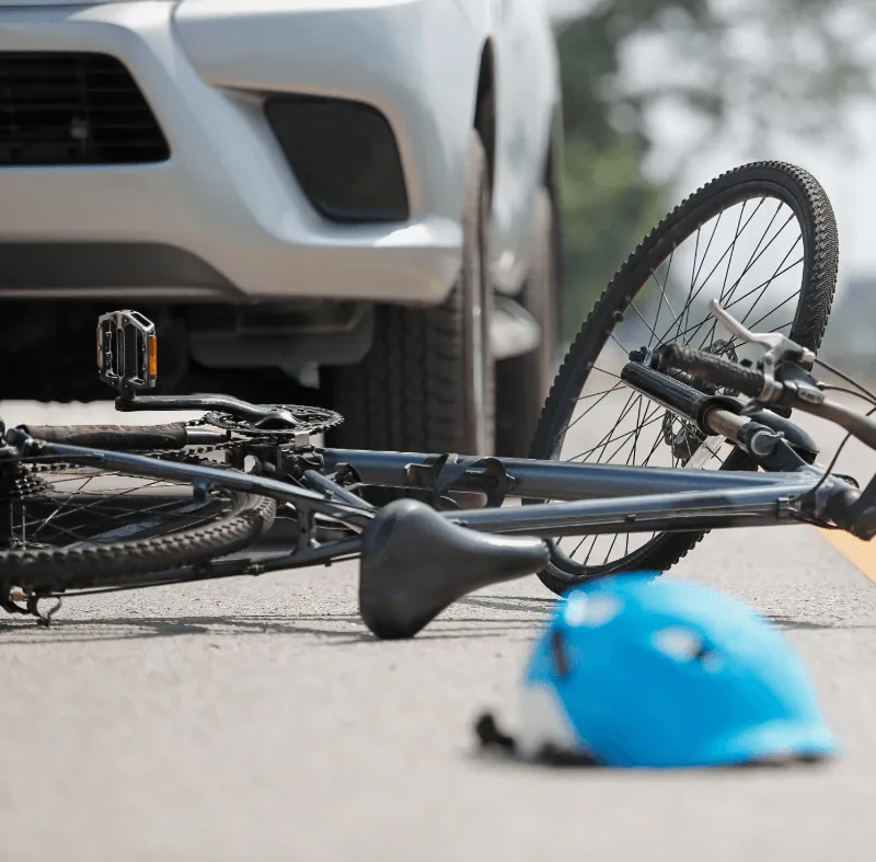 Bicycle lying in the road near a car after an accident, representing public liability risks for driving instructors.