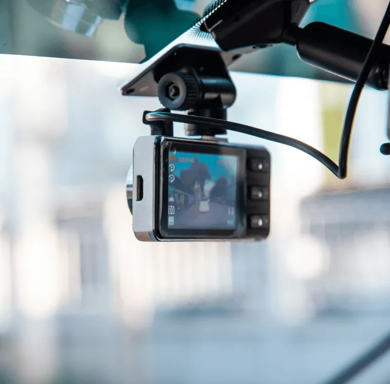 Close-up of a dashboard camera mounted on a car windshield, recording the road ahead.