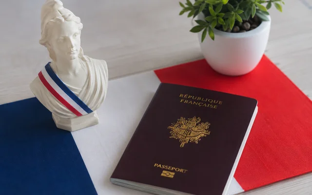 Un buste de Marianne et un passeport français posés sur un drapeau tricolore