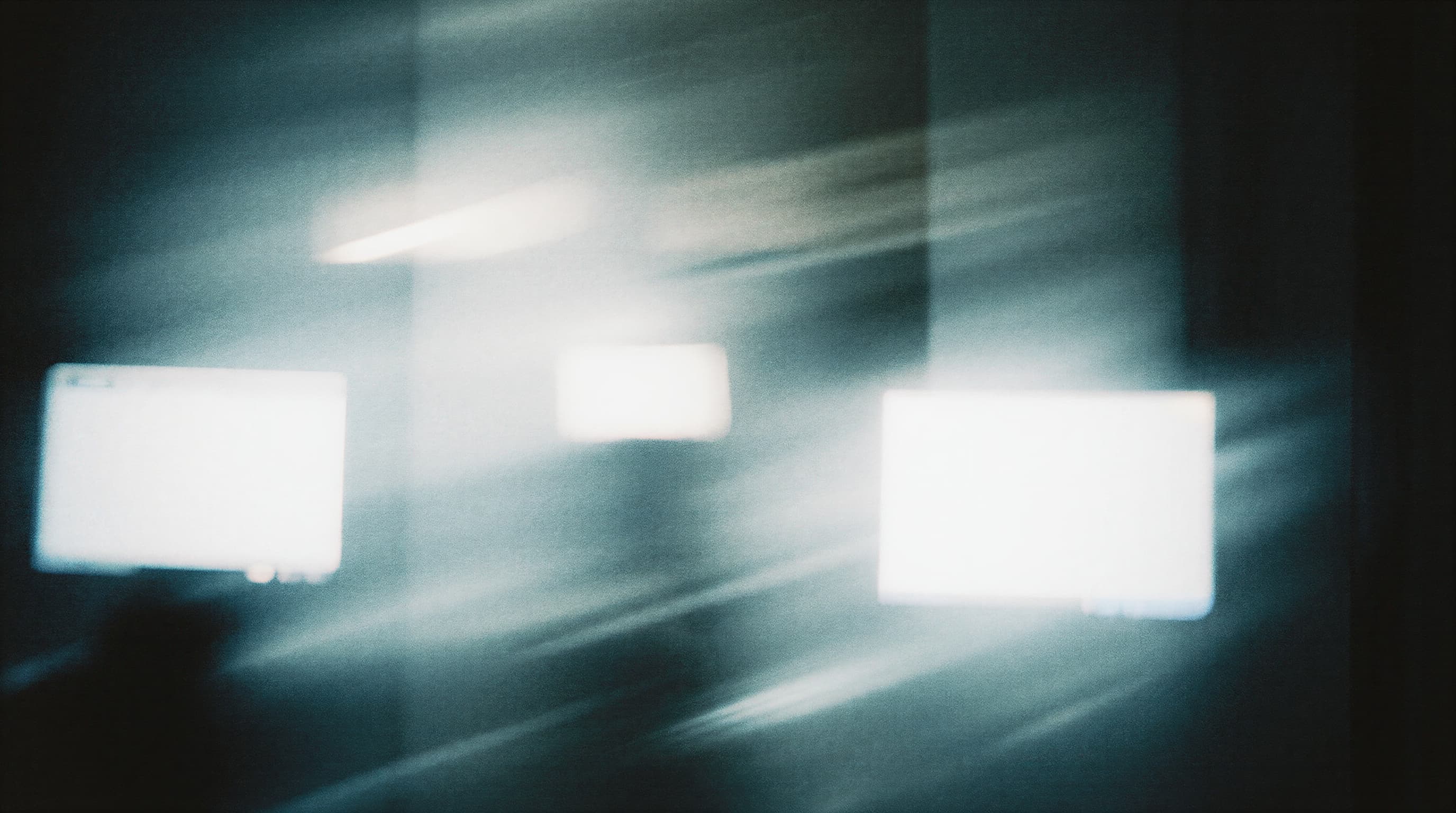 Abstract image with blurred lights and shadows, featuring a blue and white color palette, creating a sense of motion and depth.