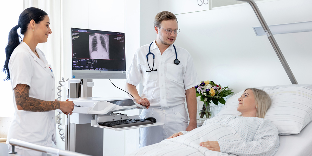 Arzt und Pflegeperson bei Patientin am Bett