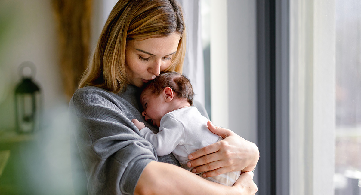 Frau trägt Baby auf dem Arm