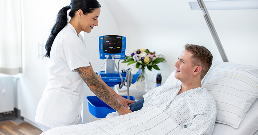 Pflegeperson bei Patient am Bett