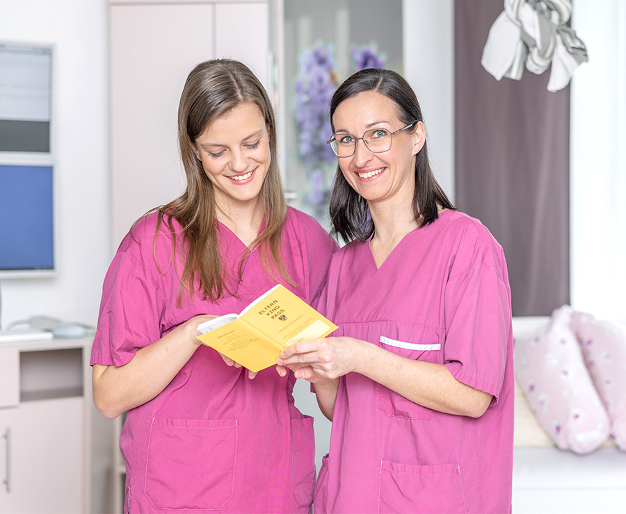Zwei Hebammen in pinker Berufskleidung
