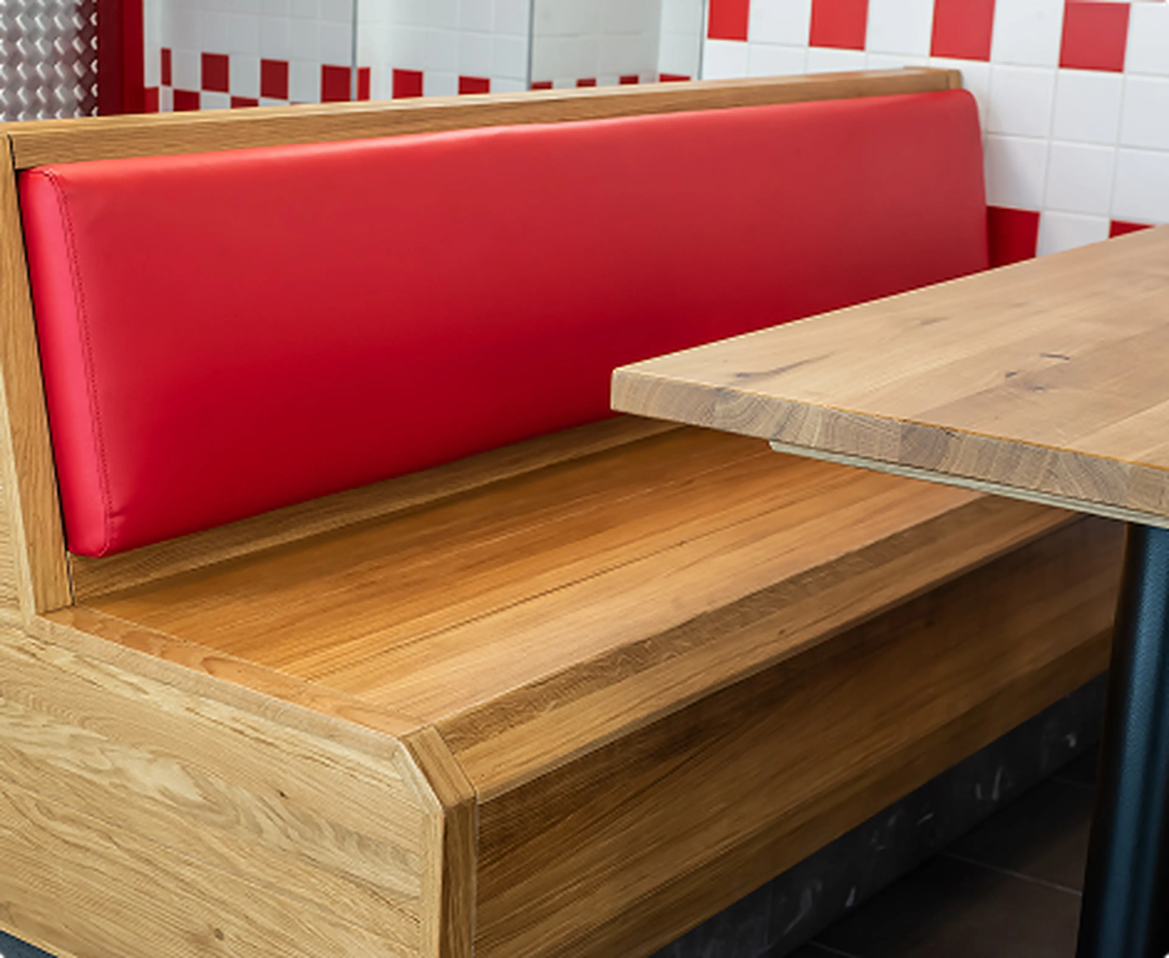 Red upholstered booth with timber seat and dining table