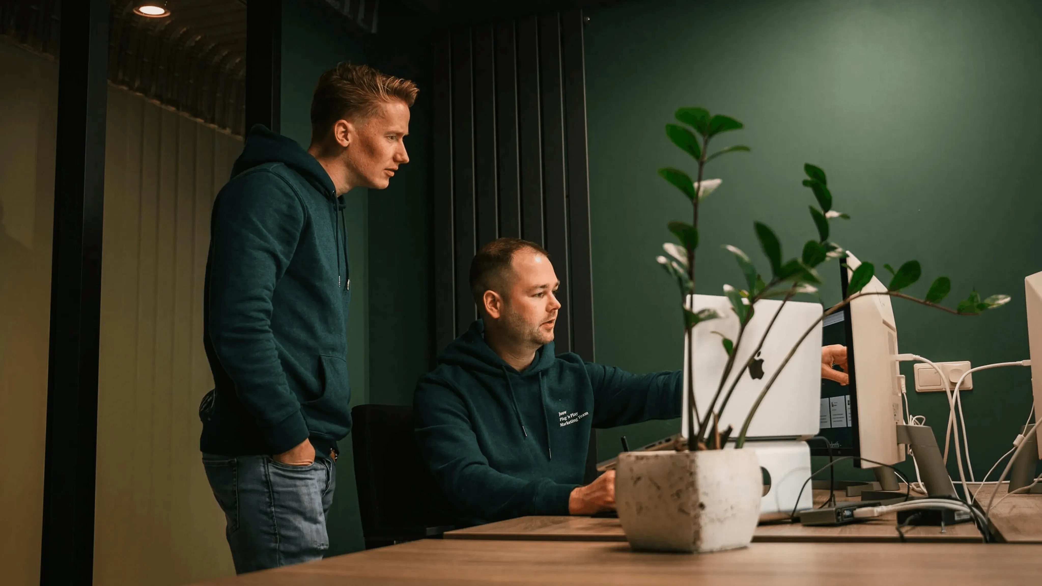 Thijs & Dries van Wedentify werken samen aan een beeldscherm in een modern, groen kantoor in Asten.