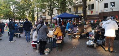 Blick auf viele Menschen, die auf Bänken sitzend das Essen einer früheren Schnippeldisko genießen. Im Hintergrund das Zelt, in dem gekocht wurde. Foto: Ernährungsrat Oldenburg