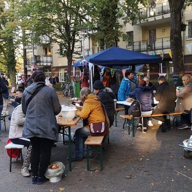 Blick auf viele Menschen, die auf Bänken sitzend das Essen einer früheren Schnippeldisko genießen. Im Hintergrund das Zelt, in dem gekocht wurde. Foto: Ernährungsrat Oldenburg