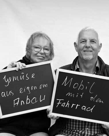 Zwei Personen aus Oldenburg zeigen ein Schild auf dem steht „Gemüse aus eigenem Anbau. Mobil mit dem Fahrrad“ Foto: Jörg Hemmen