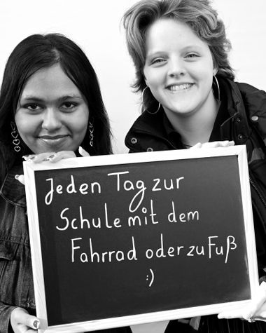 Zwei Personen aus Oldenburg zeigen ein Schild auf dem steht „Jeden Tag zur Schule mit den Fahrrad oder zu Fuß“ Foto: Jörg Hemmen