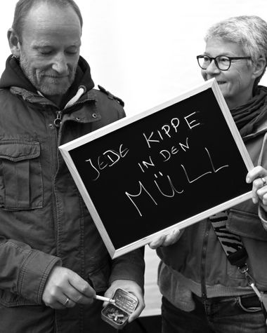Zwei Personen aus Oldenburg zeigen ein Schild auf dem steht „Jede Kippe in den Müll“ Foto: Jörg Hemmen