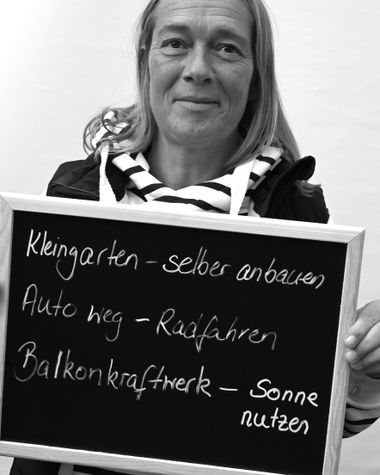 Eine Person aus Oldenburg zeigt ein Schild auf dem steht „Kleingarten - selber anbauen. Auto weg - Radfahren. Balkonkraftwerk - Sonne nutzen“ Foto: Jörg Hemmen