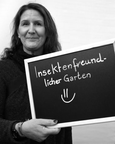Eine Person aus Oldenburg zeigt ein Schild auf dem steht „Insektenfreundlicher Garten“ Foto: Jörg Hemmen